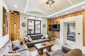 Ein modernes Wohnzimmer mit einer Sofagarnitur, einem Couchtisch und einem an der Ziegelwand befestigten Fernseher.