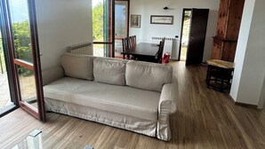 A modern living room with a sofa, a dining table, and a staircase leading to an outdoor area.