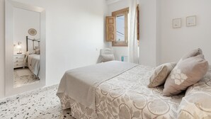 Une chambre à coucher avec un lit, une fenêtre et un miroir qui reflète la pièce.