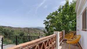 A balcony with a view of hills, a brick railing, and two yellow chairs. - Holiday Home 'La Huerta Del Parral' with Wi-Fi and Air Conditioning (Soportújar)