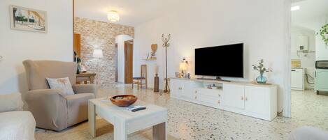 A modern living room with a sofa, a coffee table, a TV, and a fireplace.