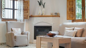 Un salon avec une cheminée, un canapé, un fauteuil et une table basse.