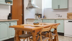 A kitchen with a wooden table, chairs, a coffee maker, and a dishwasher. - Holiday Home 'La Huerta Del Parral' with Wi-Fi and Air Conditioning (Soportújar)