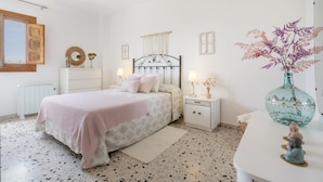 A bedroom with a bed, bedside tables, a dresser, a mirror, a window, and a decorative vase. - Holiday Home 'La Huerta Del Parral' with Wi-Fi and Air Conditioning (Soportújar)