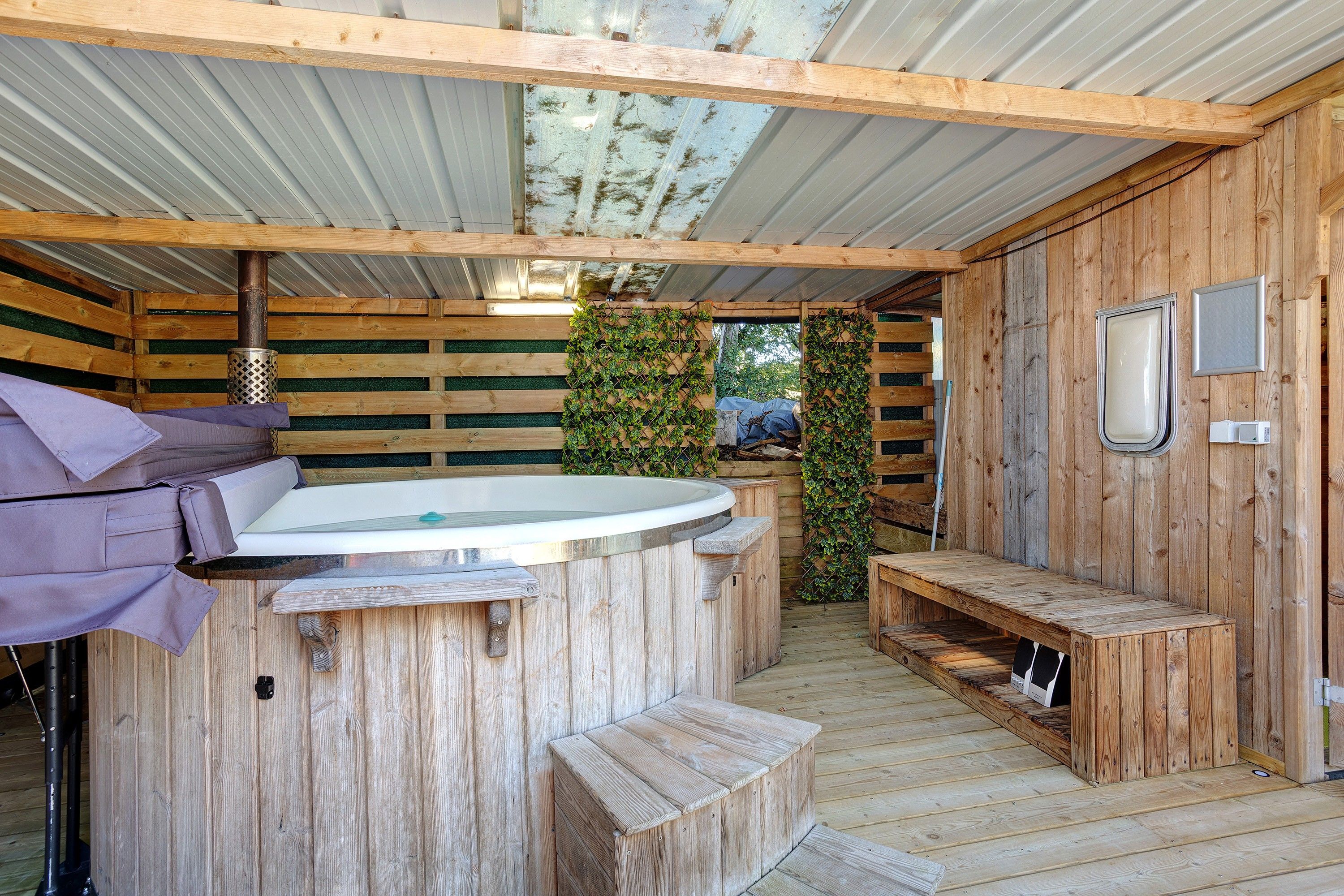 Een houten chalet met een jacuzzi, een bankje en een kleine tafel.