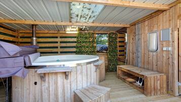Een houten chalet met een jacuzzi, een bankje en een kleine tafel.