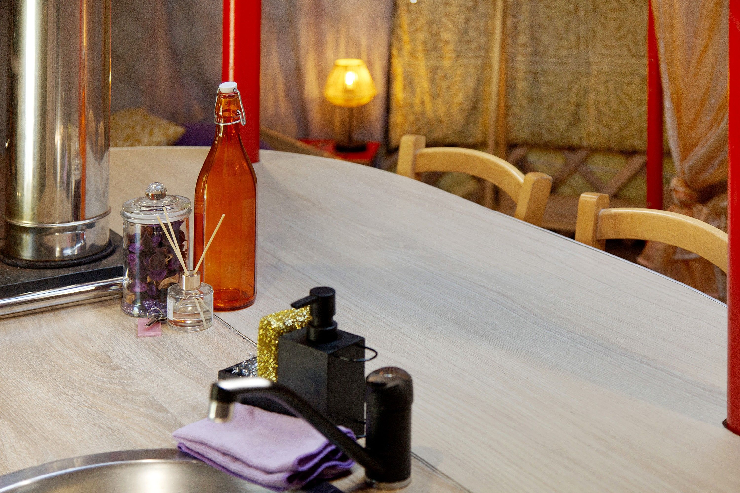 Una mesa de comedor con una botella, un frasco de vidrio y una botella pequeña con dispensador.
