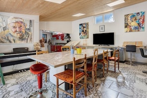 Une cuisine moderne avec un coin repas, comprenant une table en marbre, des chaises en bois et un grand tableau accroché au mur.