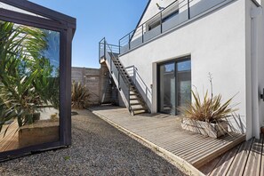 Een modern gebouw met een houten terras, een trap en een glazen deur.
