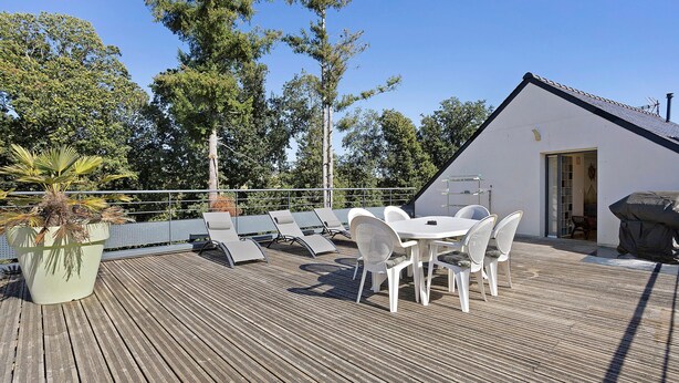 A wooden deck with a table and chairs, surrounded by trees and a white building. - In Nature – Spa – 2km from City Center (Quimper)