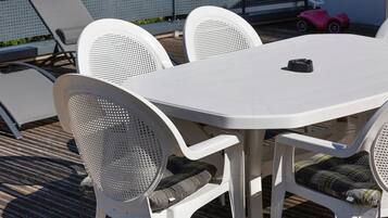Una mesa blanca al aire libre con cuatro sillas, cada una con respaldo de malla.