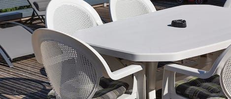 A white outdoor table with four chairs, each with a mesh backrest.