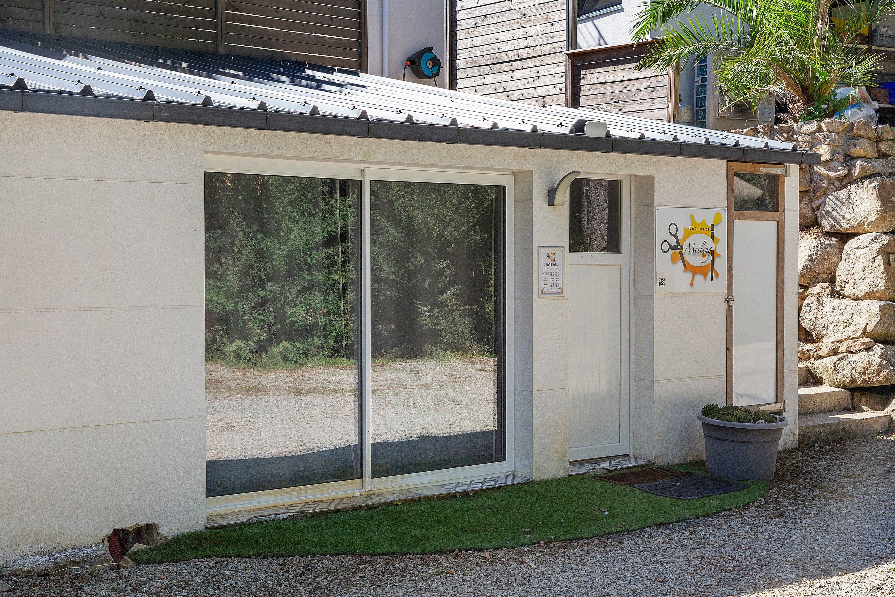 A building with a metal roof, a door with a sign, and a small garden area with a potted plant.