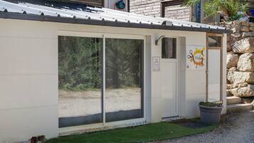 Un edificio con techo de metal, una puerta con un letrero y un pequeño jardín con una planta en maceta.