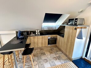 A compact kitchen with a dining area, a microwave, a toaster, and a small oven. - In Nature – Spa – 2km from City Center (Quimper)