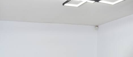 Una cama individual con cabecera marrón, ropa de cama blanca y un radiador blanco en una esquina.