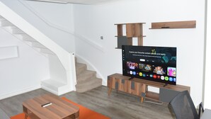 A modern living room with a staircase, a flat-screen TV, wooden furniture, and a carpeted floor. - Magic House- London (London)
