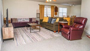 Ein Wohnzimmer mit einer Couch, einem Sessel, einem Couchtisch und einem Esstisch mit Stühlen.