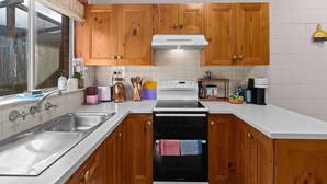 A kitchen with wooden cabinets, a stainless steel sink, a built-in oven, and a dishwasher. - Courtyard 2 Bed Apartment Mile End (Mile End)