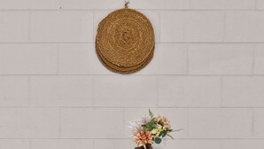 A wooden table with a vase of flowers, four stools, and a woven wall hanging. - Courtyard 2 Bed Apartment Mile End (Mile End)