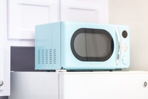 Eine hellblaue Mikrowelle auf einem weißen Gerät, mit einem weißen Schrank im Hintergrund.