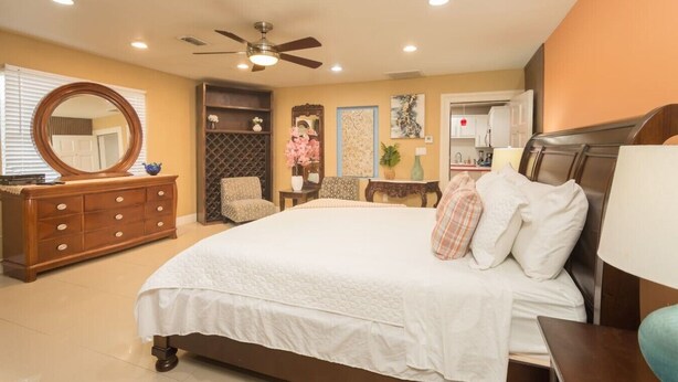 A bedroom with a bed, dresser, chair, and a ceiling fan. - The Master Suite / King Size Bed /Walk in Shower (McAllen)
