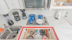 A modern kitchen with a stainless steel microwave, coffee maker, and a variety of pots and pans. - The Master Suite / King Size Bed /Walk in Shower (McAllen)
