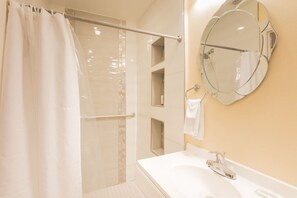 Ein Badezimmer mit Dusche, Waschbecken, Spiegel und Handtuchhalter.