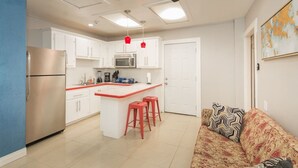 A compact kitchen with a central island, a refrigerator, and a ceiling fan. - The Master Suite / King Size Bed /Walk in Shower (McAllen)
