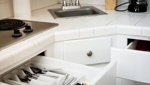 Cozinha com fogão, pia e organizador de gavetas com utensílios.