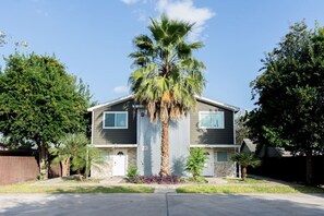 A two-story house with a central garage door, a palm tree in front, and a clear blue sky.