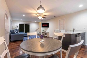 A modern living space with a dining area, kitchen, and a TV displaying 'NETFLIX'.