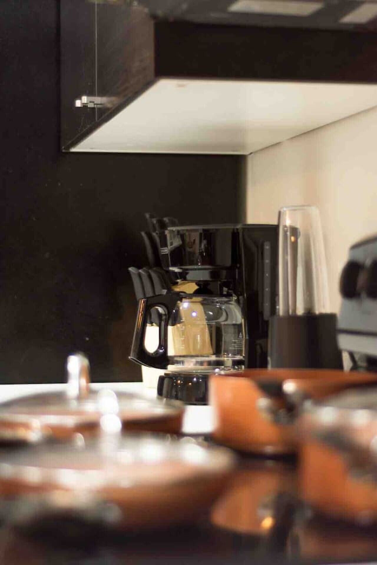 Una cocina con cafetera, licuadora y diversos utensilios de cocina.