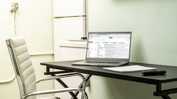 A laptop on a desk with a notebook and remote control beside it. - Central Junior Suite Fast-WiFi  First Floor (McAllen)
