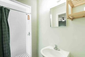 Ein Badezimmer mit Dusche, Waschbecken und Spiegel.