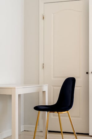 A chair with a dark seat and gold legs, positioned in front of a white door.