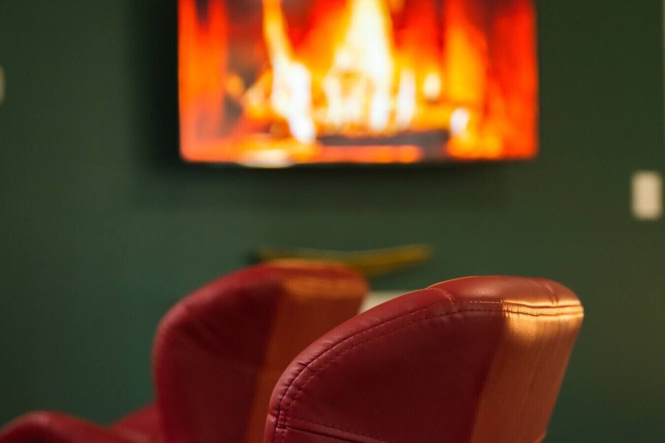 A room with a fireplace, a red chair, and a green wall.
