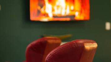 A room with a fireplace, a red chair, and a green wall.