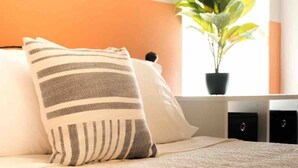 A bed with a striped pillow, a potted plant, and a window with blinds. - Fast Wi-Fi Spacious & Cozy Central DT Home (McAllen)