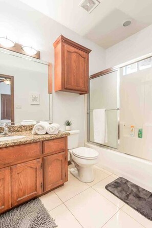 A bathroom with a wooden vanity, a sink, a toilet, and a shower area.