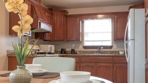 A kitchen with wooden cabinets, a microwave, a sink, and a refrigerator. - Fast Wi-Fi Spacious & Cozy Central DT Home (McAllen)