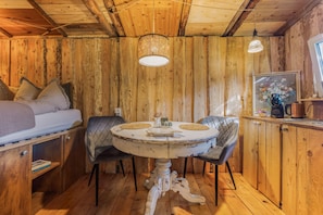 A cozy cabin interior with a bed, a round dining table, and a coffee station. - Holiday Home 'Glamping Cottage with Hot Tub' with Private Pool, Private Terrace and Wi-Fi (Hipstedt)