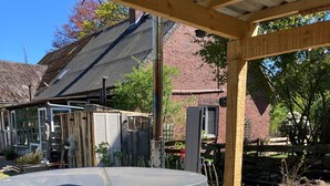 Una vasca idromassaggio in legno con scalini, un gazebo in legno e una sedia in un giardino con fondo in ghiaia.