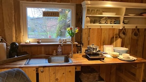 Una cucina con mobili in legno, un lavello, un fornello e una finestra vista giardino.