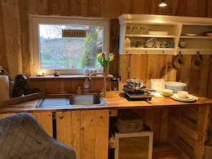 Una cocina con armarios de madera, un fregadero, una estufa y una ventana con vistas a un jardín.