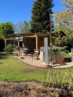 Une cabane en bois avec un patio, un barbecue et un petit jardin.