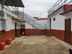 Ein Gebäude mit einer Treppe zu einer oberen Ebene, einer Tür rechts und einem überdachten Bereich mit Dach.