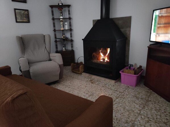 Un salon avec une cheminée, un canapé, un téléviseur et un meuble en bois.