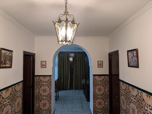 A hallway with patterned walls, a chandelier, and framed pictures on the walls. - Casa Rural Villagarcia – Comfort and Privacy in El Real de la Jara (El Real de la Jara)