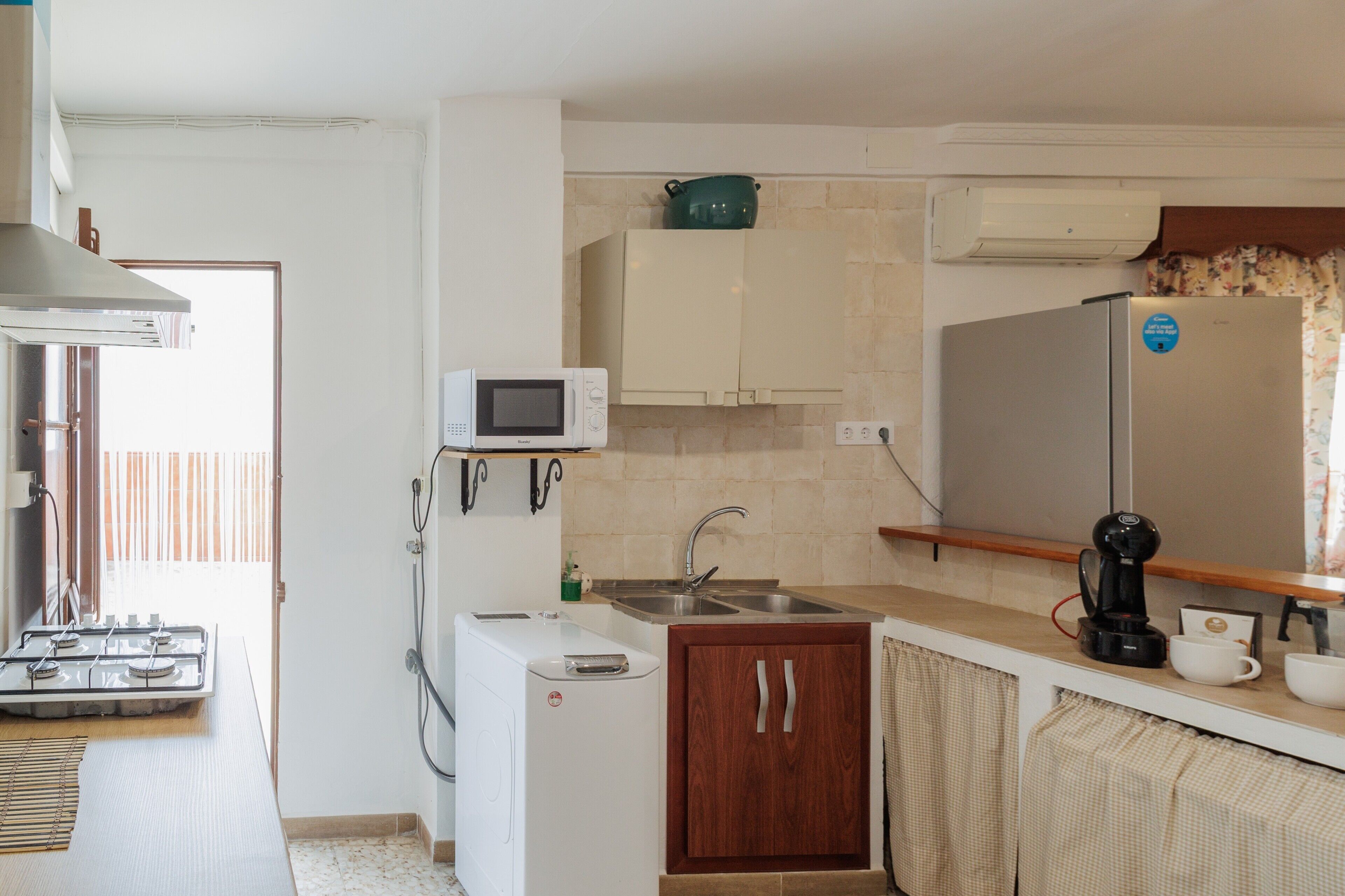 A compact kitchen with a gas stove, microwave, sink, and a refrigerator.